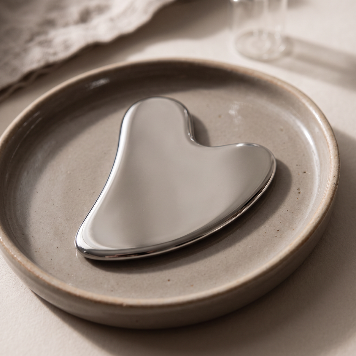 Colder Mornings gua sha board - close-up on ceramic tray